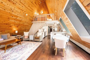 Ein Loft-Interieur mit Holzboden, einem Essbereich, einer Treppe und einem großen Fenster.