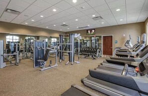 Ein Fitnessstudio mit Laufbändern, Kraftgeräten und Kurzhanteln.
