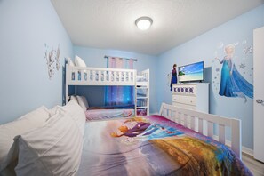 Ein Kinderzimmer mit Etagenbetten, einem Fernseher und einem Wandgemälde einer Figur.