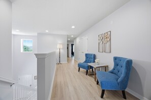 Ein Flur mit Treppe, einer Stehlampe und zwei blauen Sesseln.