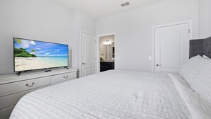 Quarto com cama grande, televisão sobre uma cômoda e porta que dá para um banheiro.
