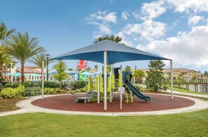 Ein Spielplatz mit blauem Baldachin, Rutschen und Spielgeräten.