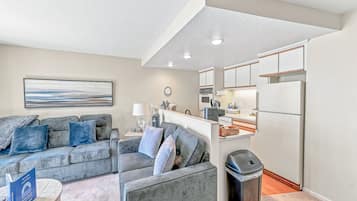 A modern living room with a grey sofa, a coffee table, and a trash bin.