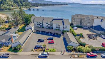 A multi-story hotel with a parking lot, adjacent to a body of water with boats.