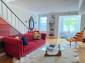 A modern living room with a red sofa, a glass coffee table, and a white shag rug.
