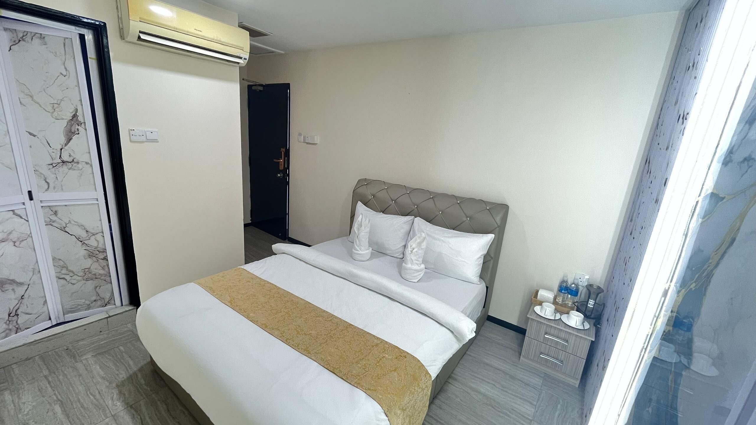 Une chambre d’hôtel comprenant un lit, une table de chevet avec des articles de toilette et une porte donnant sur une autre pièce.