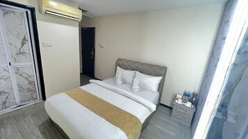 Habitación de hotel con cama, mesita de noche con artículos de aseo y puerta que da a otra habitación.