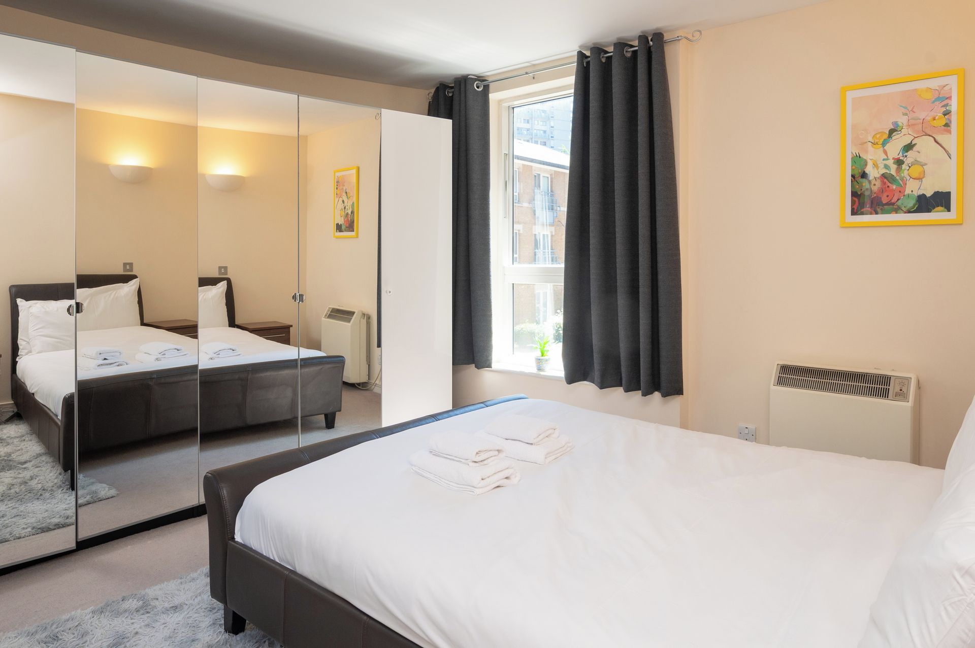 Ein Hotelzimmer mit zwei Betten, einem großen Spiegel, einem Fenster mit Vorhängen und einer Heizung.