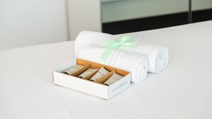 A white box with a green ribbon, containing rolled white towels and a white box with a label. - {Suite 501} Gym, Business Room, Modern, Relax (Lugano)