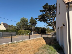 A fenced outdoor area with dry grass, a white building, and trees. - La Baule, between the sea and the countryside, 5 minutes from the golf course, 3.9 km from the beach. (La Baule-Escoublac)