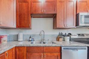 A kitchen with wooden cabinets, a stainless steel sink, a coffee maker, and a dish soap bottle. - Seattle 2 Bedroom 1 Bath Suite (Seattle)