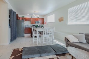 A modern kitchen with wooden cabinets, a central island, and white chairs. - Private Remodeled 2BR · Fenced Yard · Free Parking · Laundry · Pets OK (Seattle)