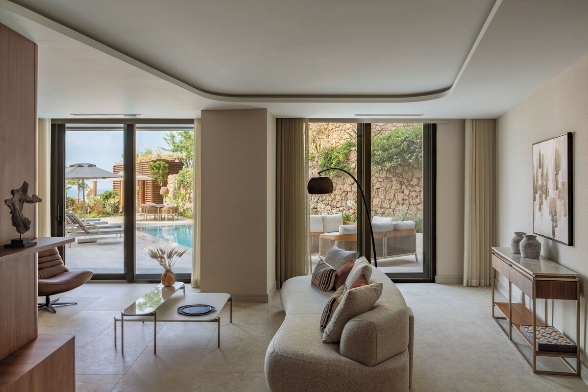 Una sala de estar moderna con vista a la piscina, un sofá, una mesita de centro y un mueble consola.