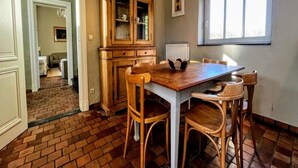 Un'area pranzo con un tavolo e sedie in legno, un mobile con ante in vetro e una finestra con tende.