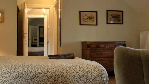 Una camera da letto con un letto, una cassettiera e due quadri appesi al muro.
