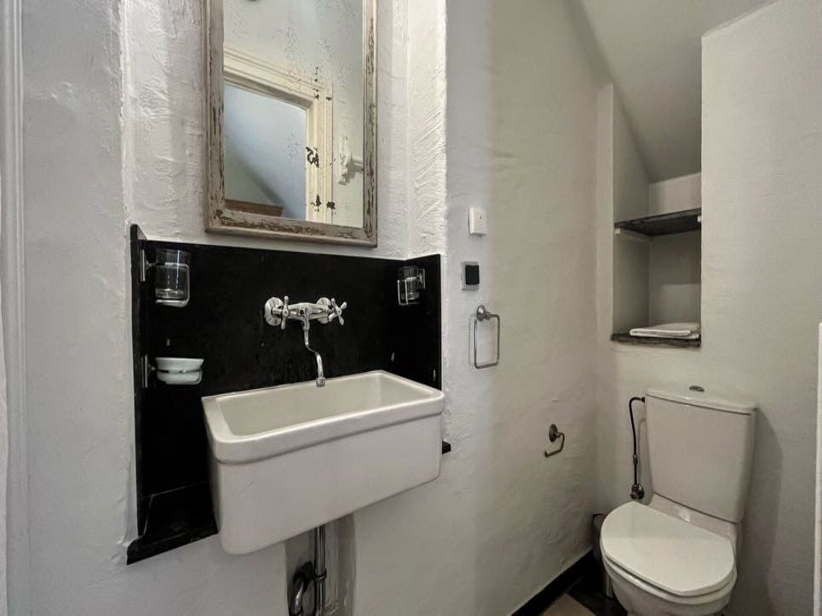 A bathroom with a white sink, a mirror, and a toilet.