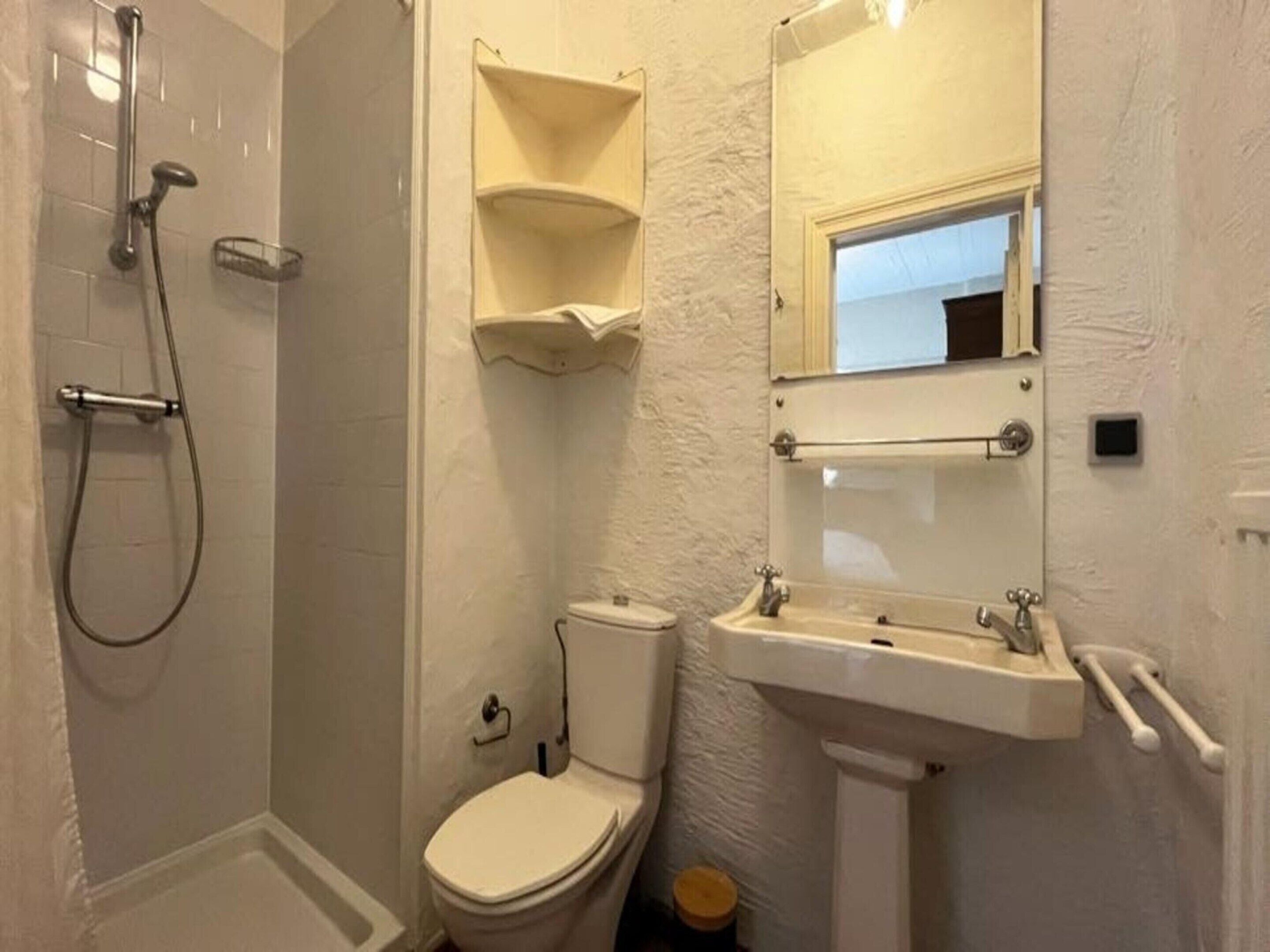 A bathroom with a shower, toilet, and sink.