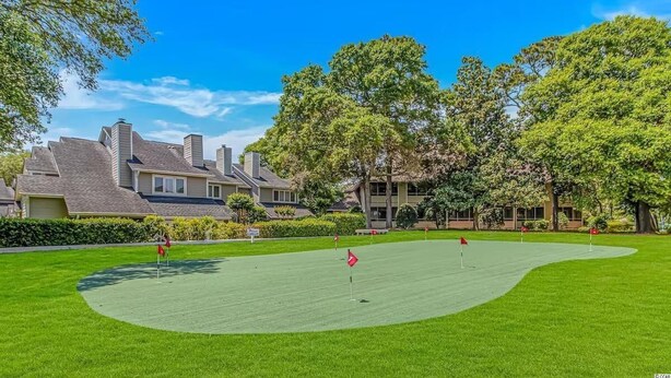 Ein Golfplatz mit Putting Green, umgeben von Wohngebäuden und Bäumen.