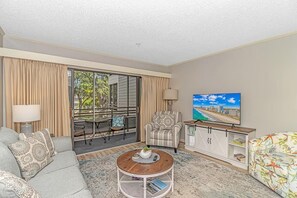 A living room with a sofa, armchair, coffee table, and a painting on the wall. - Ocean Creek Resort: 7-min walk to beach (Myrtle Beach)