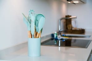 Eine Küche mit einem hellblauen Utensilienhalter, der Kochutensilien mit Holzgriffen enthält.