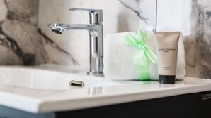 Uma casa de banho com uma pia de mármore, uma toalha e um frasco de condicionador Balsamo.