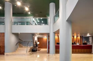 A modern hotel lobby with a reception desk, a staircase, and a second-floor balcony. - Apartamentos Premium da Berrini by Conviva (São Paulo)