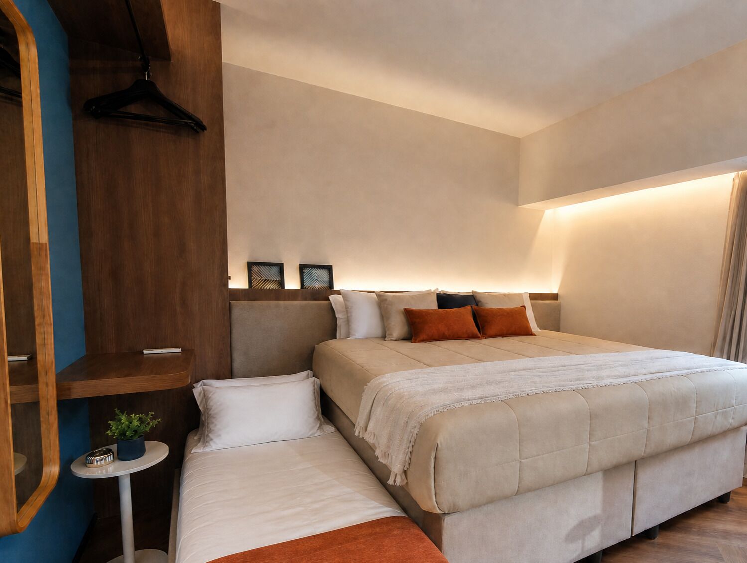 Ein modernes Schlafzimmer mit einem großen Bett, Nachttischen, einer Pendelleuchte und einer kleinen Pflanze.
