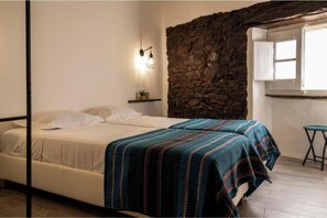 A bedroom with a bed, a stone wall, a window, and a nightstand. - D. Alzira's Corner - Monsaraz (Distrito de Évora)