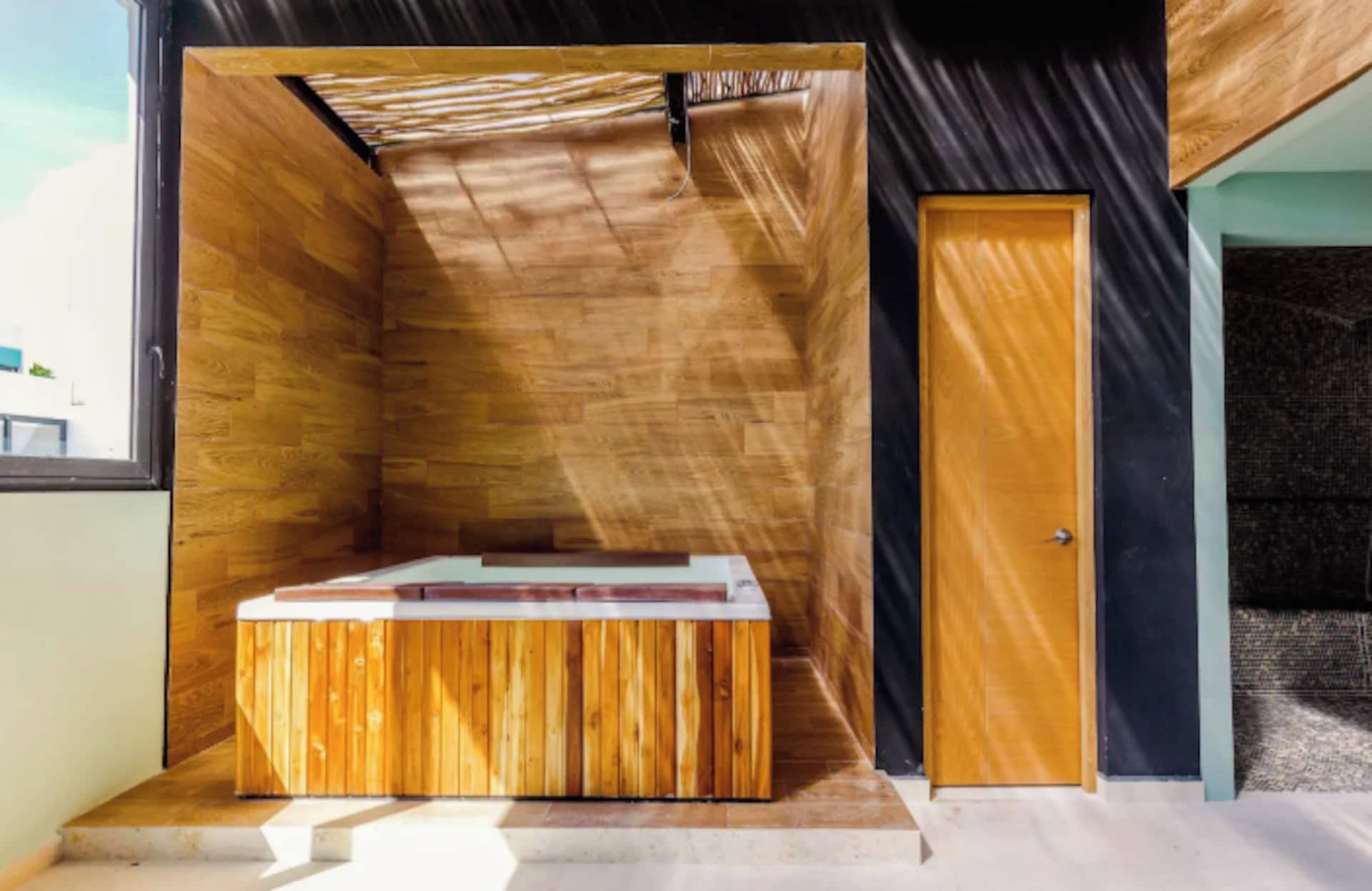 Een moderne badkamer met een houten wastafelmeubel, een douche en een deur.