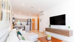 Ein modernes Wohnzimmer mit einer Couch, einem Couchtisch und einem an der Wand befestigten Fernseher.