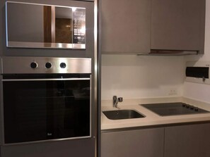 Eine moderne Küche mit eingebautem Backofen, Spüle und Mikrowelle.