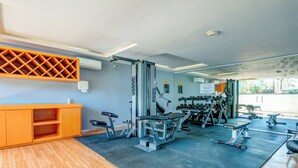 Een sportschool met diverse fitnessapparaten, een receptiebalie en een wandairconditioning.