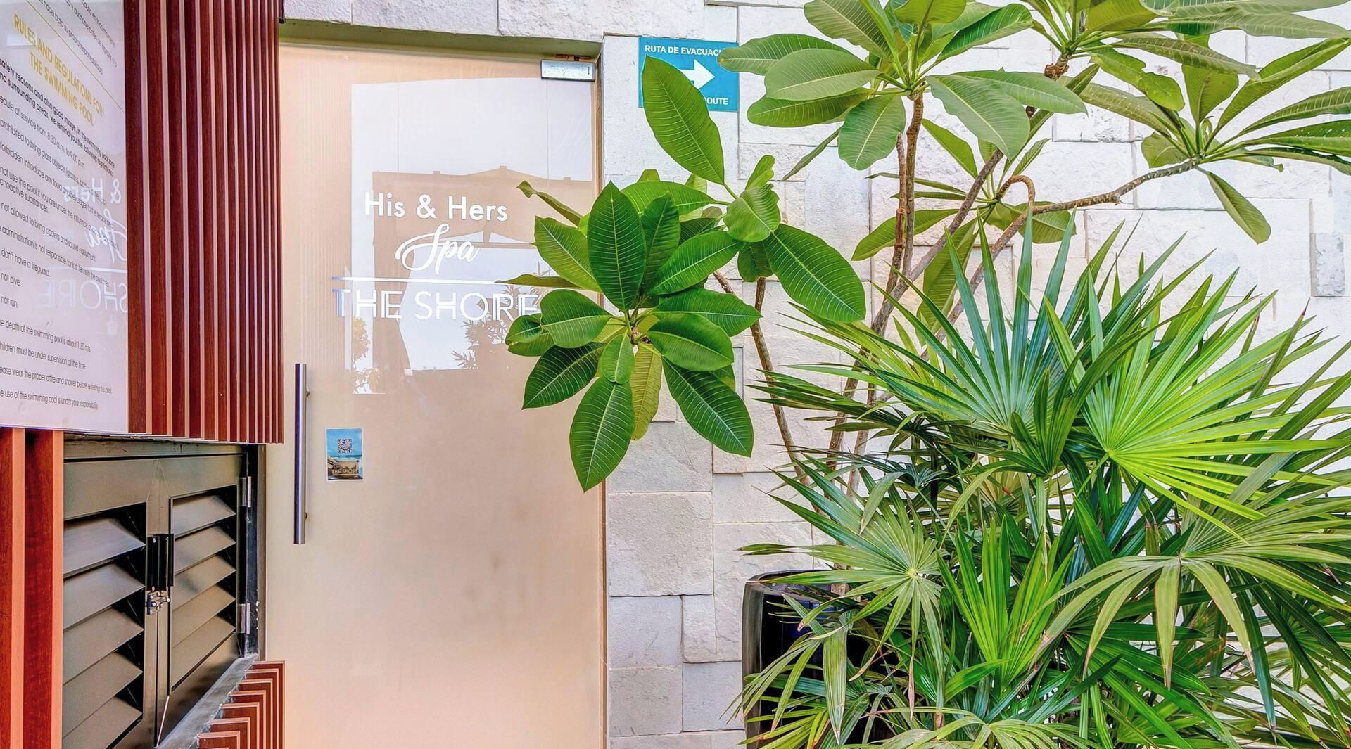 Eingang zum Spa mit einem Schild für 'His & Hers Spa The Shore' und einem sichtbaren Notausgang-Hinweis.