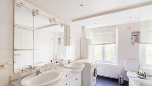 A modern bathroom with two sinks, a large mirror, and a built-in washing machine. - Brugman Area Self Check in Apartment for 5 (Brussels)