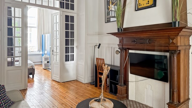A room with a fireplace, a television, and a window with curtains. - Brugman Area Self Check in Apartment for 5 (Brussels)