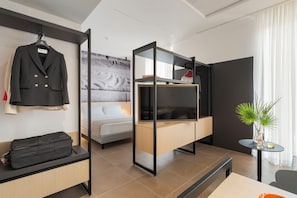Una habitación de hotel moderna con cama, escritorio, armario y perchero.
