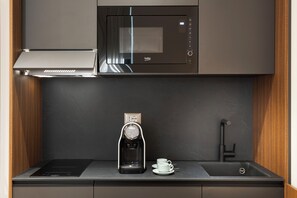 Cozinha moderna com micro-ondas embutido, máquina de café e pia.