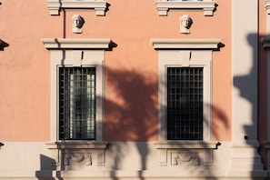 Fachada de edifício com duas janelas, molduras decorativas e um pilar central.