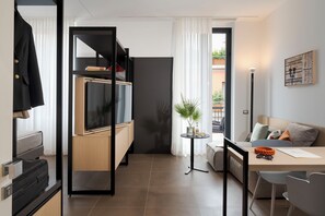 Un espacio habitable moderno y funcional con kitchenette, comedor y zona de estar con vistas al exterior.