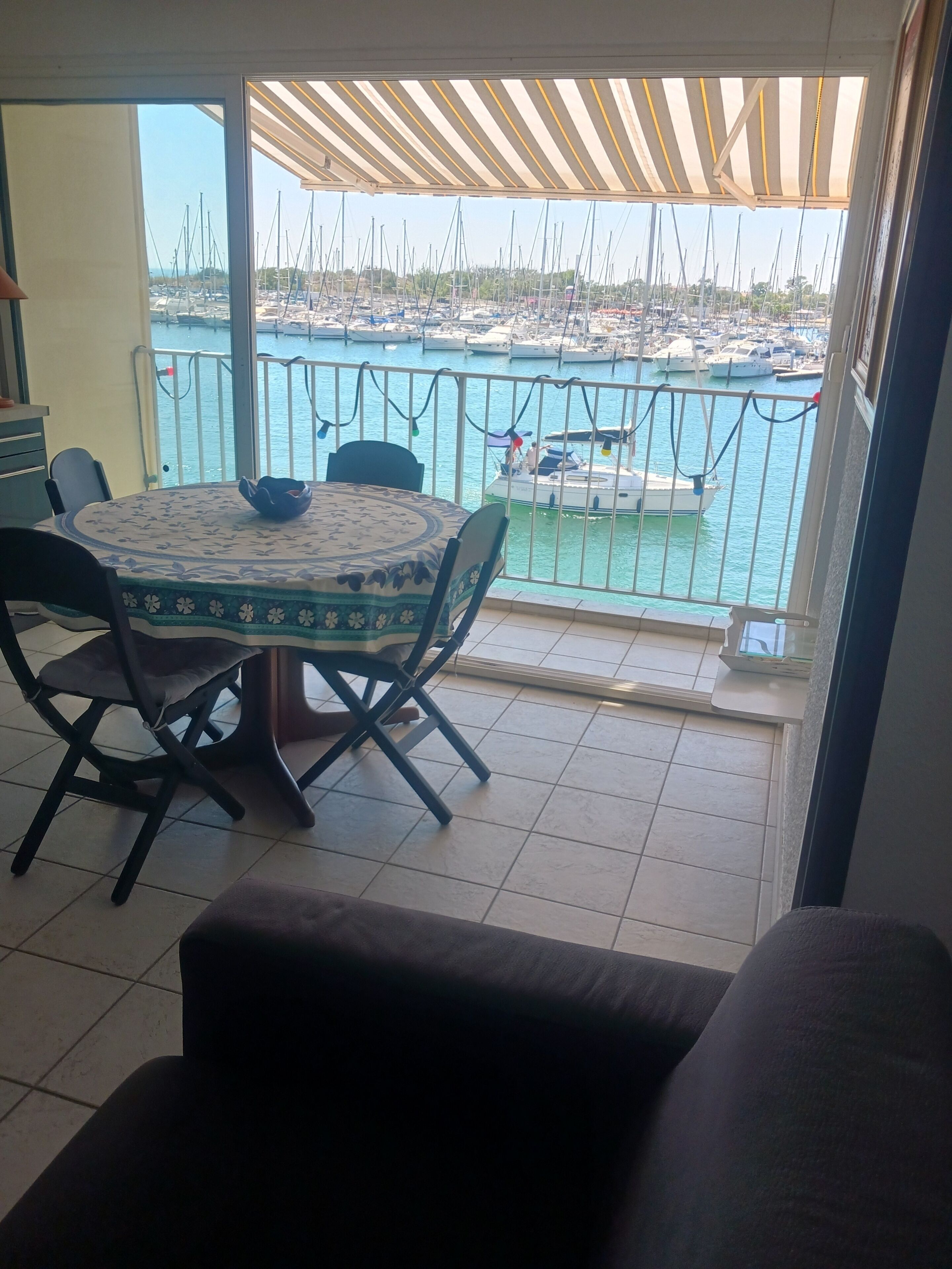 Ein Essbereich mit Tisch und Stühlen, Blick auf eine Marina mit Booten und einem gefliesten Boden.