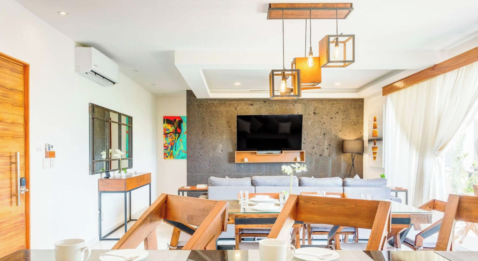 A modern living room with a flat-screen TV, wooden furniture, and a stone accent wall.