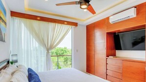 A bedroom with a bed, a ceiling fan, a TV, and a window with curtains. - Beachside retreat w/ rooftop pool & BBQ (Playa del Carmen)