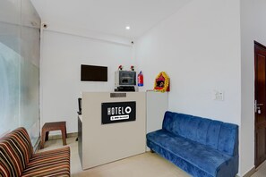 A hotel reception area with a reception desk, a blue sofa, a striped sofa, and a small table. - Classic With Balcony Gomti Nagar Station (Lucknow)