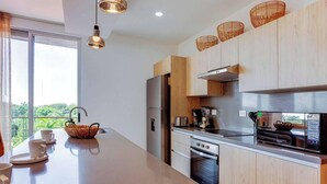 A modern kitchen with a large island, stainless steel appliances, and a view of greenery outside. - Ocean-view retreat w/ pool & parking (Playa del Carmen)