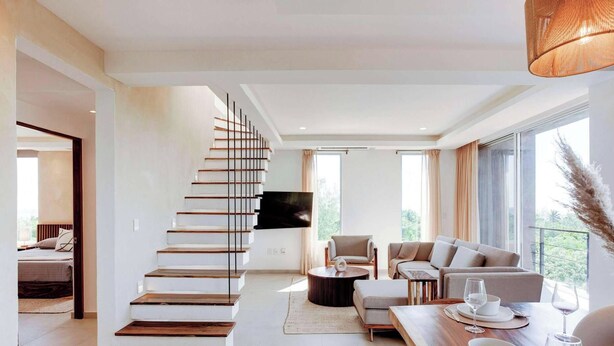 A modern living room with a staircase, a flat-screen TV, a sofa set, and a dining area with a table and chairs. - Ocean-view retreat w/ pool & parking (Playa del Carmen)
