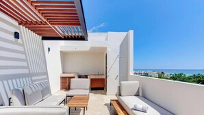 A balcony with a seating area, a small table, and a view of the ocean. - Ocean-view retreat w/ pool & parking (Playa del Carmen)