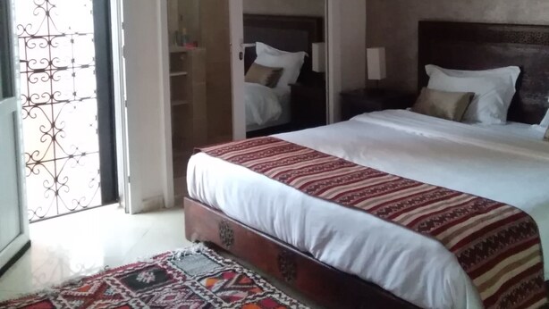 A bedroom with a bed, a patterned rug, a wooden headboard, and a ceiling fan. - Cozy Villa in Downtown Agadir (Agadir)