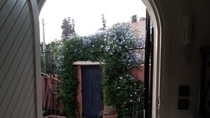 An open doorway leading to a tiled patio area with a potted plant and a blue curtain. - Cozy Villa in Downtown Agadir (Agadir)