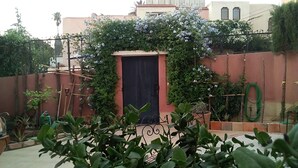 A courtyard with a door, potted plants, and a garden hose. - Cozy Villa in Downtown Agadir (Agadir)