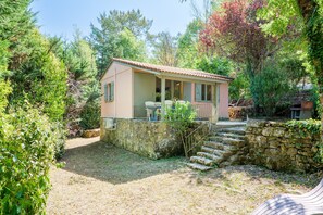A small, single-story building with a tiled roof, a covered porch, and a stone wall. - Chalet 'Confort Piscine Partagée' with shared pool, communal terrace and Wi-Fi (Les Vans)